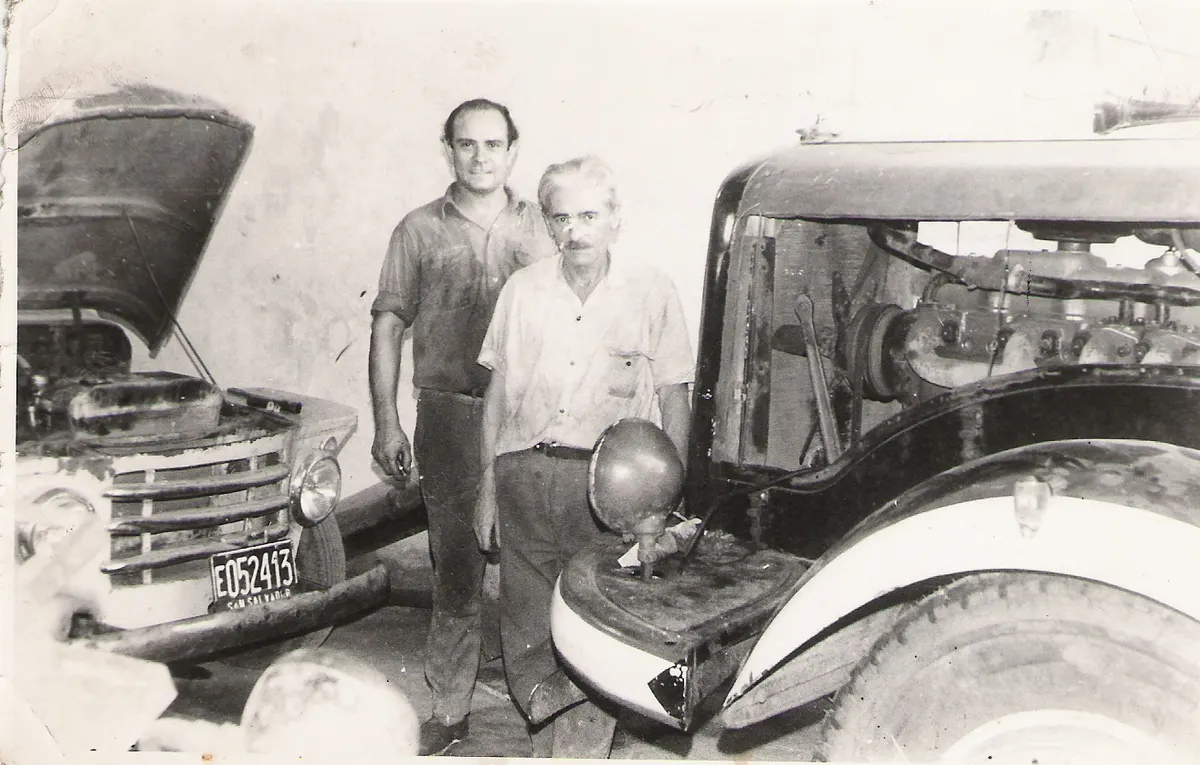 Dos mecánicos posando junto a un camión de la época en el taller, en una foto de archivo en blanco y negro