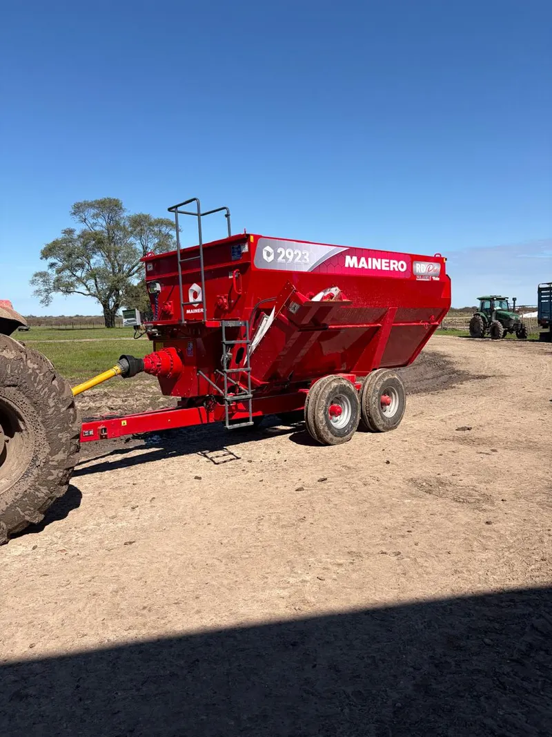 Tolva autodescargable Mainero 2923 enganchada a un tractor, en el campo